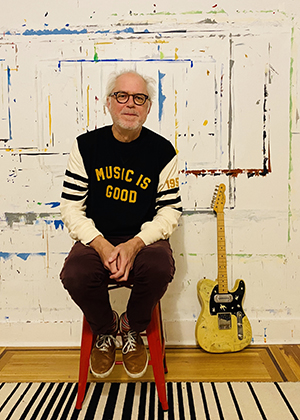 Guitarist Bill Frisell sits on a stool wearing a shirt that says &quot;Music is good,&quot; a Fender Telecaster guitar by his side.