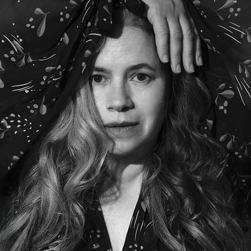 Singer-songwriter Natalie Merchant poses with her hands on her head.