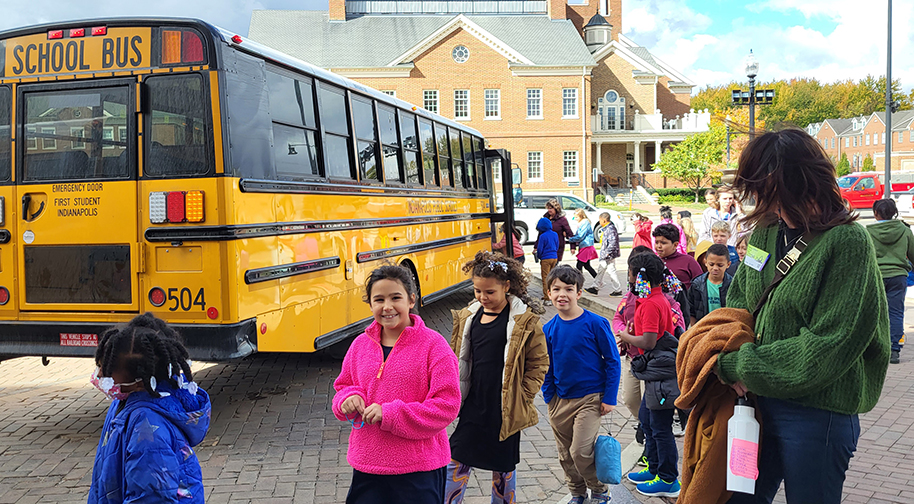 Children and teachers exit a yellow school bus outside the Palladium.