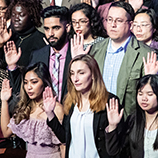 People from many nations raise their hands to take the U.S. Oath of Allegiance