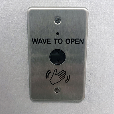 A metal plate on a wall reads &quot;Wave to open&quot; with a drawing of a waving hand.