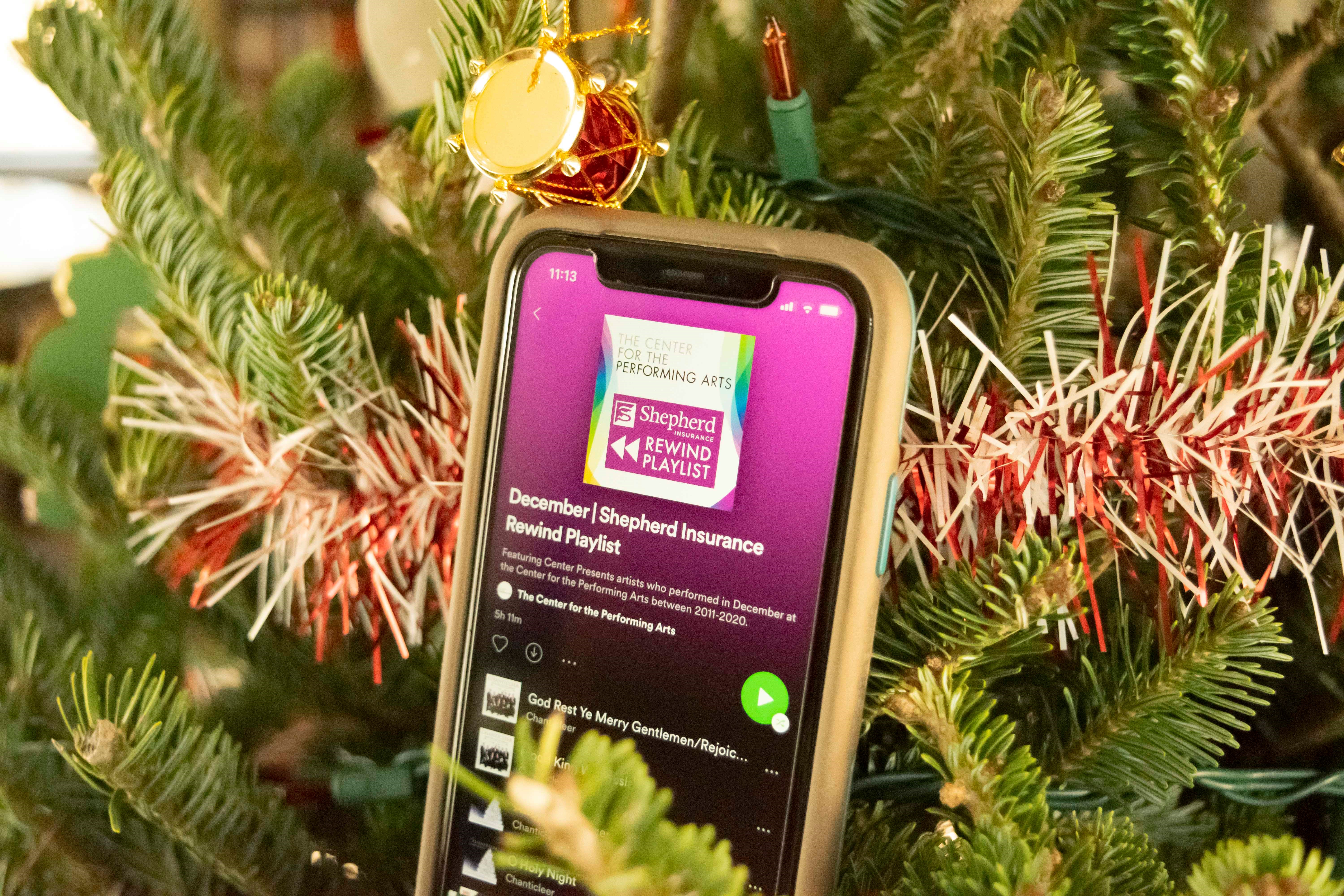 A smart phone hangs in a Christmas tree