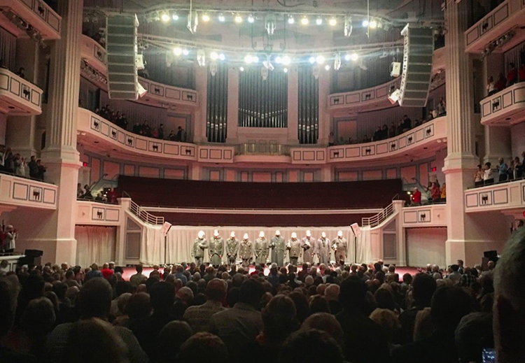 Ten actors dressed as soldiers stand on the Palladium stage.