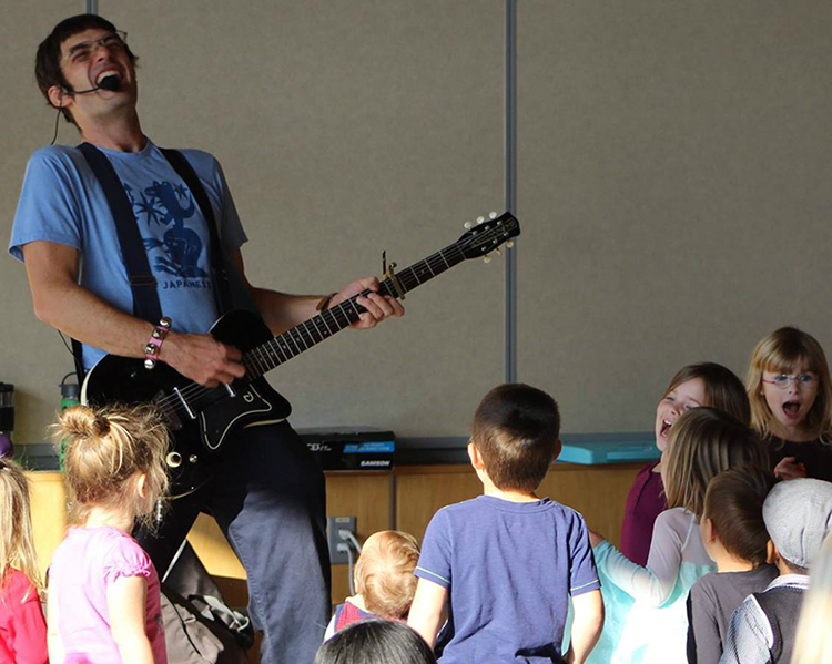 Children&#x27;s performer Mr. Daniel plays guitar for a group of children