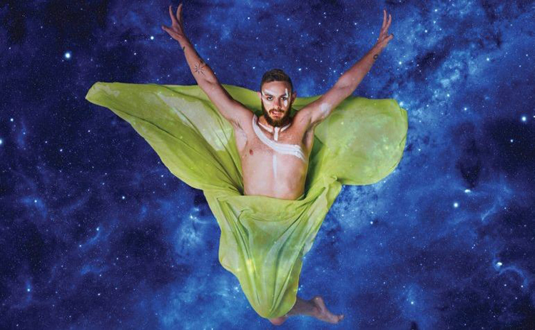 A dancer leaps in the air, wrapped in green cloth.