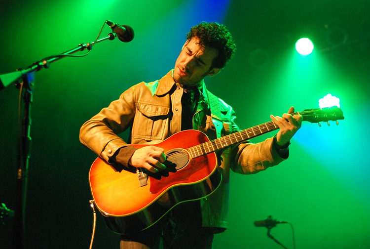 Nashville musician Adam Ollendorf plays an acoustic guitar on stage.