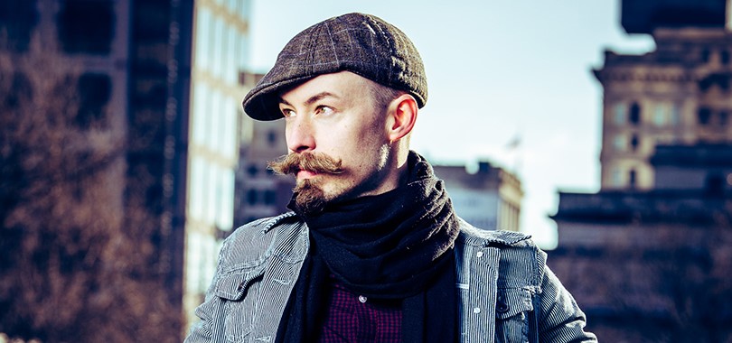 Singer-songwriter Tommy Icarus poses in a suit and cap