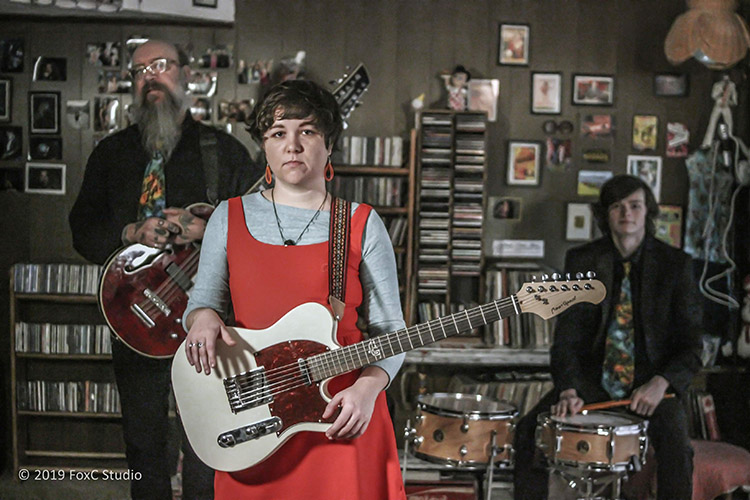 Meghan Cristeen Martin and her two bandmates pose with their instruments.