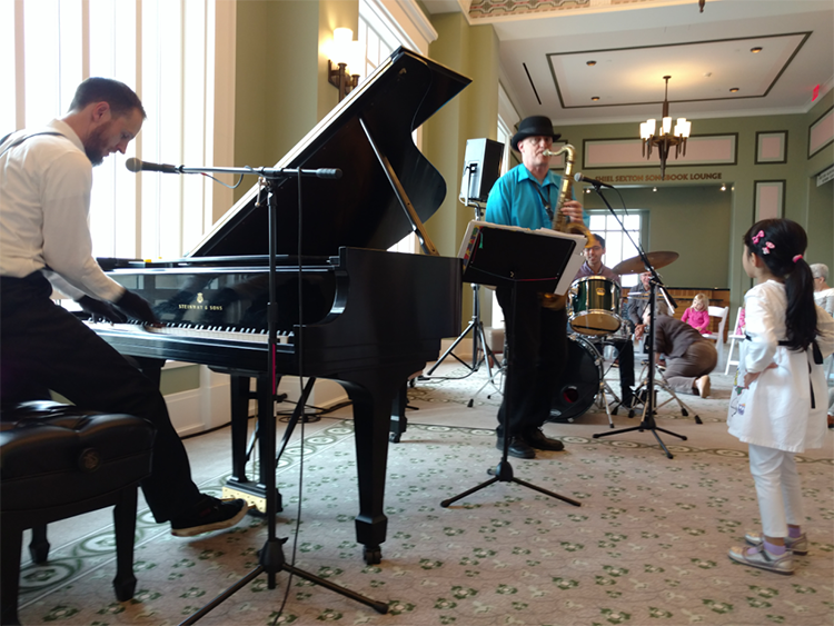 A piano trio performs for small children.