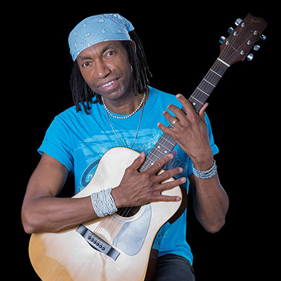A man wearing a bandana holds an acoustic guitar