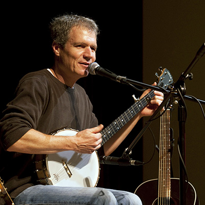 A man playing a banjo and singing into a microphone