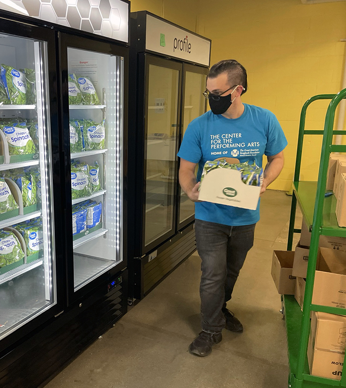 A man places frozen vegetable packages in a freezer.