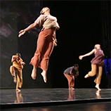 Dancers on a stage leap into the air