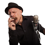 Musician Tad Robinson blows a harmonica into a vintage microphone