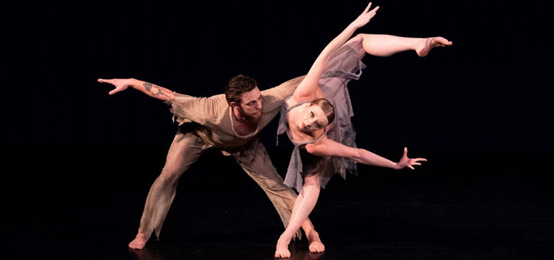Two dances, one man and one woman, in nude colored loose fitting costuming strike a pose of dramatic angles.
