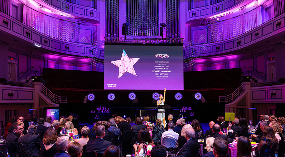 A large screen shows a star filling with confetti as guests at the Center Celebration donate to pass the $140,000 goal.