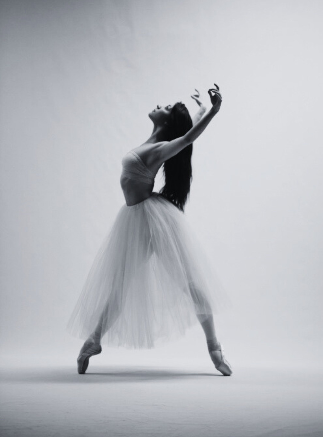 A woman with long dark hair dances in ballet style
