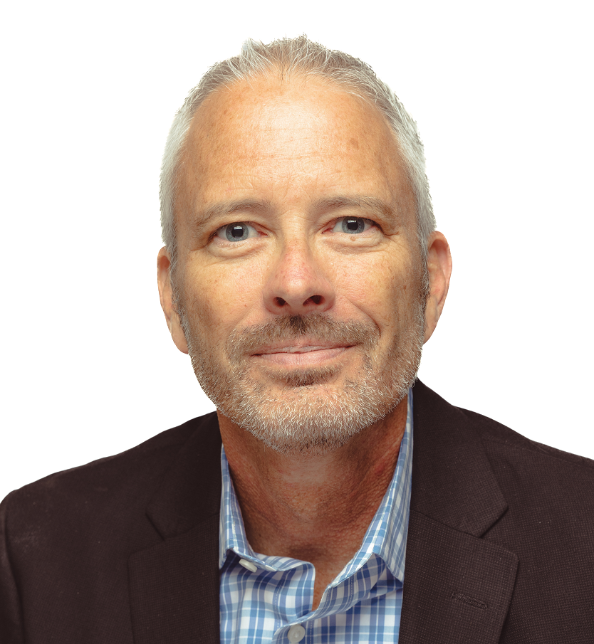 A man in a dark suit and blue shirt smiles for a headshot